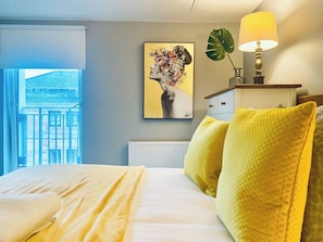 Une chambre d’hôtel avec un lit, un tableau, une lampe et une vue sur un bâtiment à l’extérieur.