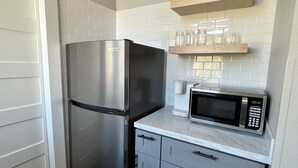 A compact kitchen with a stainless steel refrigerator, a microwave, and grey cabinets. - Newly Renovated "Arctic Rose" Loft in Historic Florence (Florence)