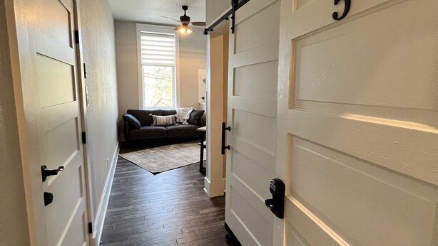 A hallway with a wooden floor, a sliding door marked with the number 5, and a couch in the background. - Newly Renovated "Arctic Rose" Loft in Historic Florence (Florence)