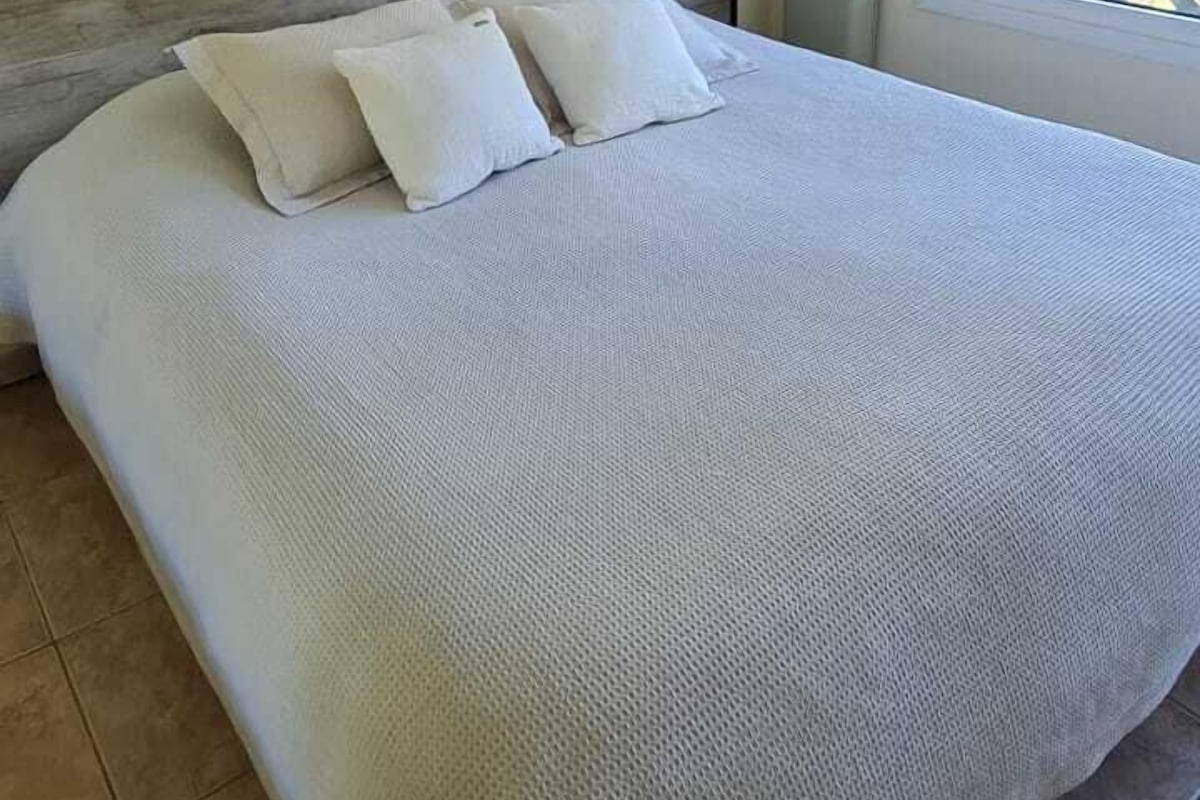 Une chambre à coucher avec un grand lit, une tête de lit, une fenêtre et un climatiseur fixé au mur.