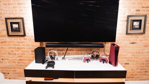 A flat-screen TV mounted on a brick wall with a white entertainment unit below. - Modern Smart Home w/Gourmet Kitchen, Peloton & King Suite  with Rooftop Deck (Baltimore)