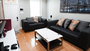 A living room with two black sofas, a white coffee table, and a ceiling fan. - Modern Smart Home w/Gourmet Kitchen, Peloton & King Suite  with Rooftop Deck (Baltimore)