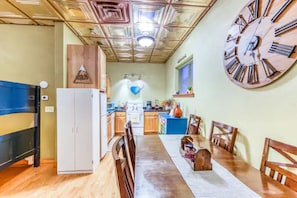 A compact kitchen with a dining area, wooden cabinets, a refrigerator, and a large clock on the wall. - The Lovemore Inn (Delta)