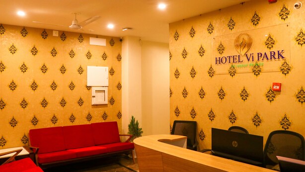 Zona de recepción de un hotel con un sofá rojo, mostrador de madera y varios portátiles HP.