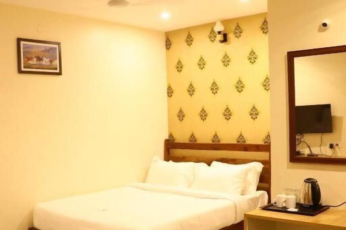 Una habitación de hotel con cama, escritorio, espejo y papel tapiz estampado.