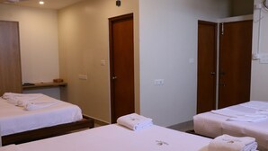 Habitación de hotel con dos camas, cada una con toallas dobladas y un pequeño logotipo en la colcha.