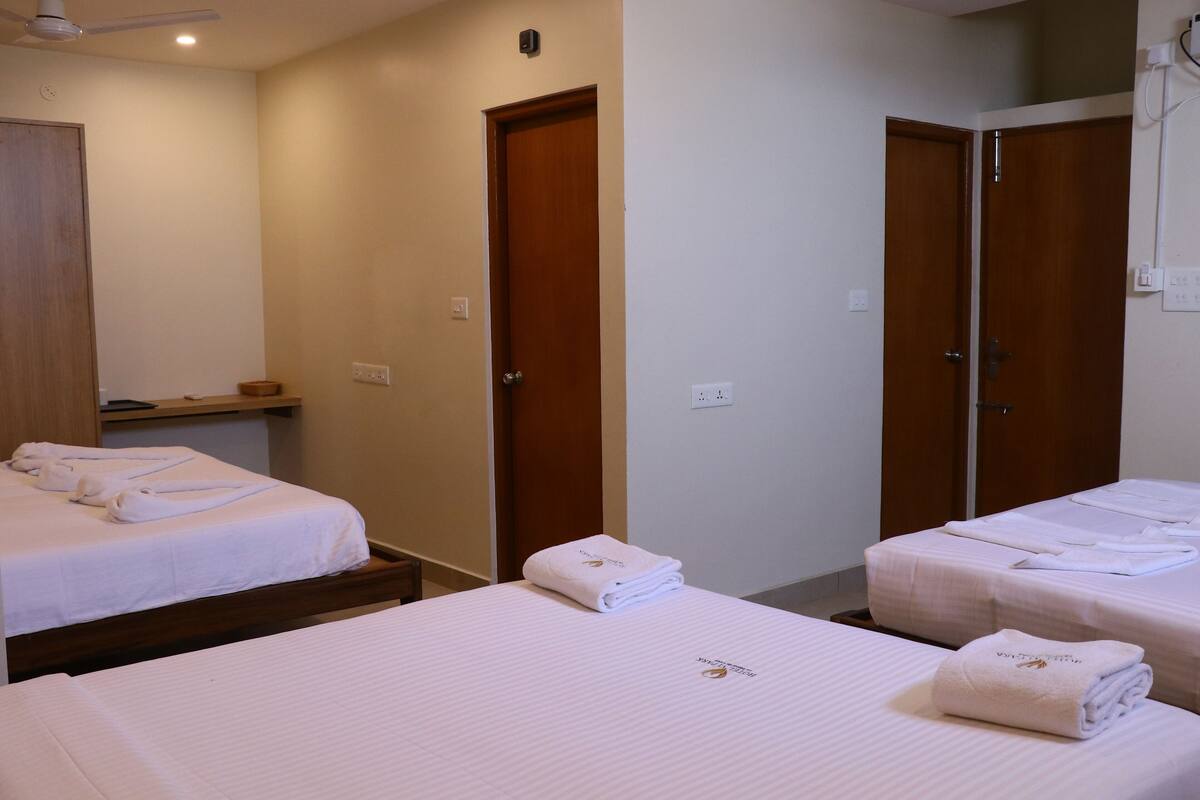 Habitación de hotel con dos camas, cada una con toallas dobladas y un pequeño logotipo en la colcha.