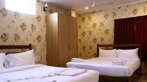 Habitación de hotel con dos camas, un armario y papel tapiz con motivos florales.