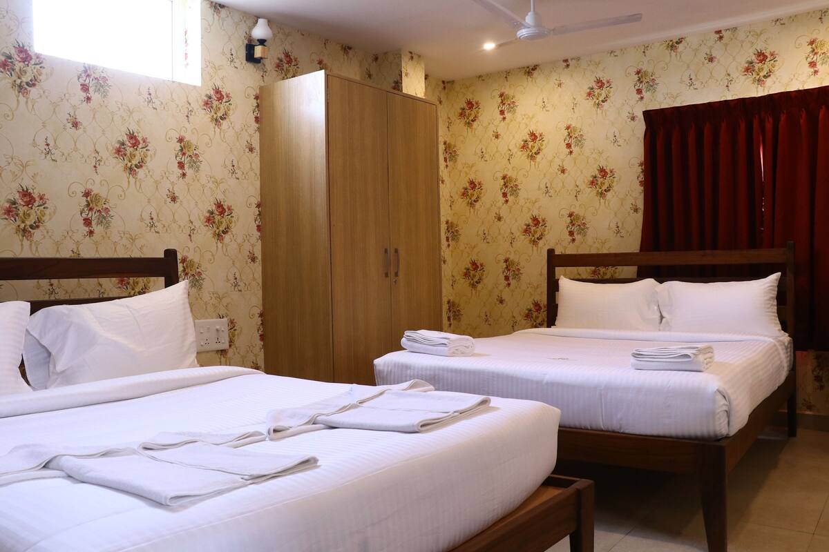 Habitación de hotel con dos camas, un armario y papel tapiz con motivos florales.