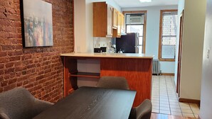 A modern kitchen with wooden cabinets, a black refrigerator, and a window with a view. - Studio boutique à 2 min do Central Park (New York)