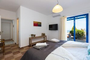 Ein Schlafzimmer mit einem Bett, einem Fernseher, einer Bank und Blick ins Freie.