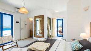 Ett modernt hotellrum med en säng, en stol, ett skrivbord och utsikt över havet.