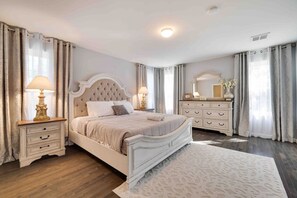 Ein Schlafzimmer mit einem Bett, Nachttischen, einem Schminktisch und einem Spiegel.
