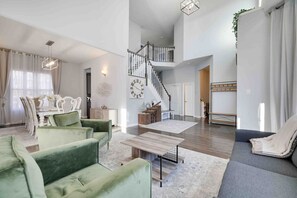 Un amplio espacio habitable con una escalera, un comedor y una sala de estar con sofás.