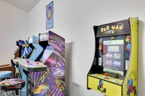 Arcade machines with 'Pac-Man' and 'Turtles in Time' labels, a 'nickelodeon' branded stool, and a framed picture on the wall. - Luxury Modern 6BR Pocono Home Near All Attractions (Tobyhanna)