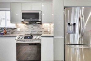A modern kitchen with stainless steel appliances, a microwave, and a built-in oven. - Luxury Modern 6BR Pocono Home Near All Attractions (Tobyhanna)