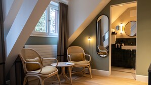Una habitación acogedora con dos sillones de mimbre, una mesita redonda y un espejo grande en la pared.