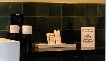 A hotel reception area with a green tiled wall, a digital clock, and a sign promoting environmental awareness.
