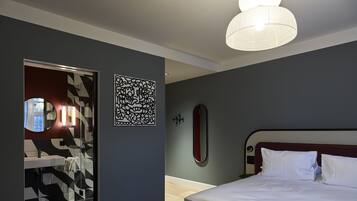 Un dormitorio moderno con una cama grande, una mesita de noche, un espejo y una pared decorada con arte abstracto.