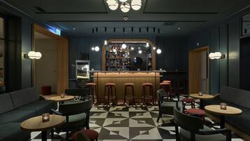 Eine Bar mit Hockern, einer Theke und einer Sitzecke mit Sofas und Tischen.