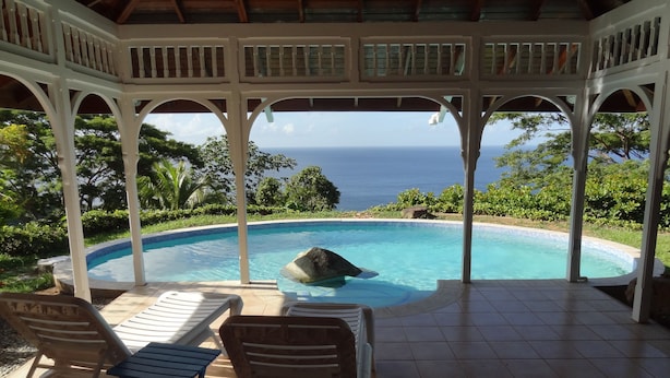 A covered pool area with a view of the ocean, featuring a gazebo, lounge chairs, and a tiled floor. - Beautiful, secluded, open plan cottage with spectacular sea views (Castara)