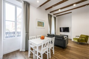 Una sala de estar con una mesa de comedor blanca, un sofá gris y un sillón verde.