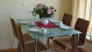 Een eettafel met stoelen, een vaas met bloemen en een schilderij aan de muur.