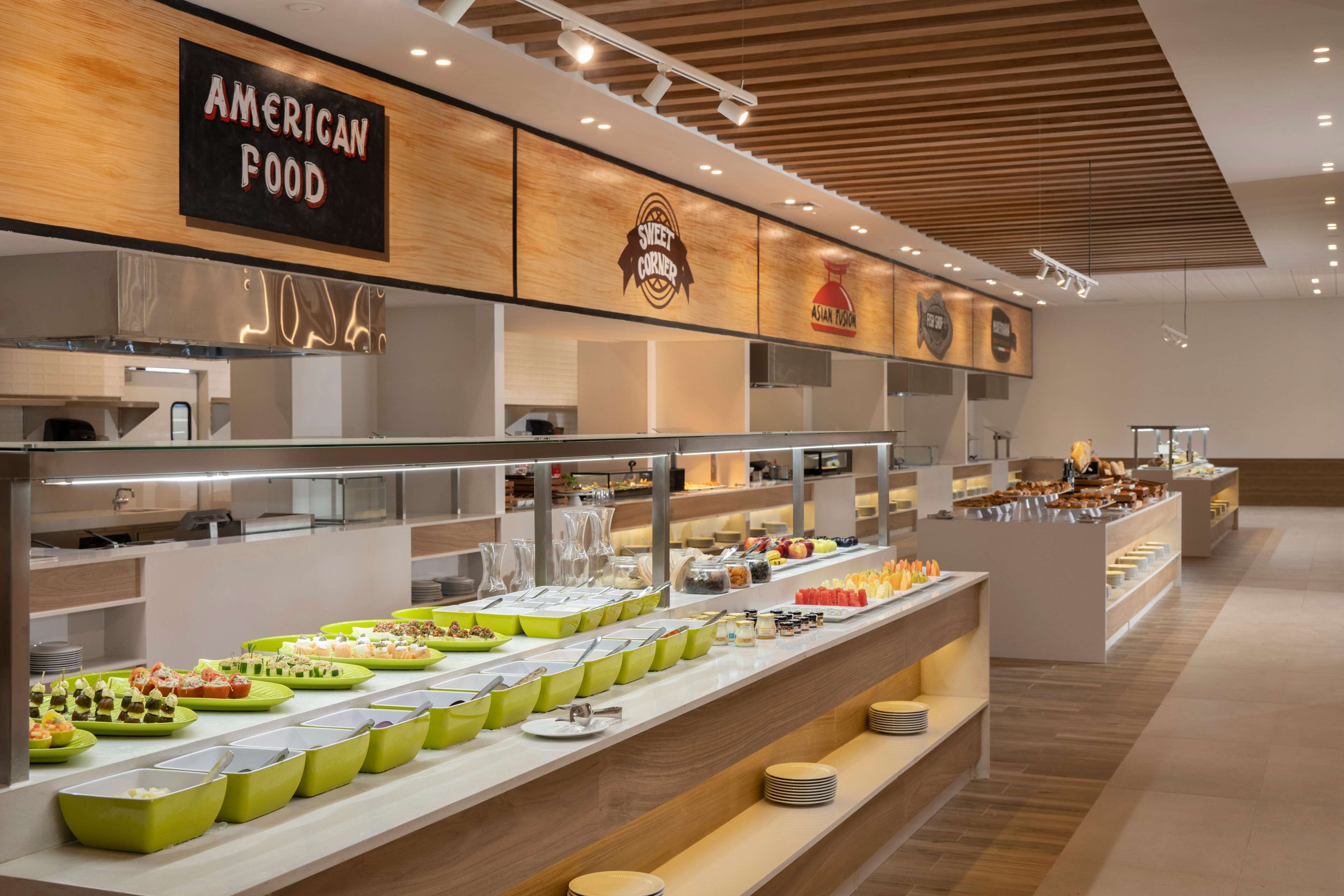 Buffet com diversas estações de comida, incluindo culinária americana e asiática, e um letreiro indicando 'Sweet Corner'.