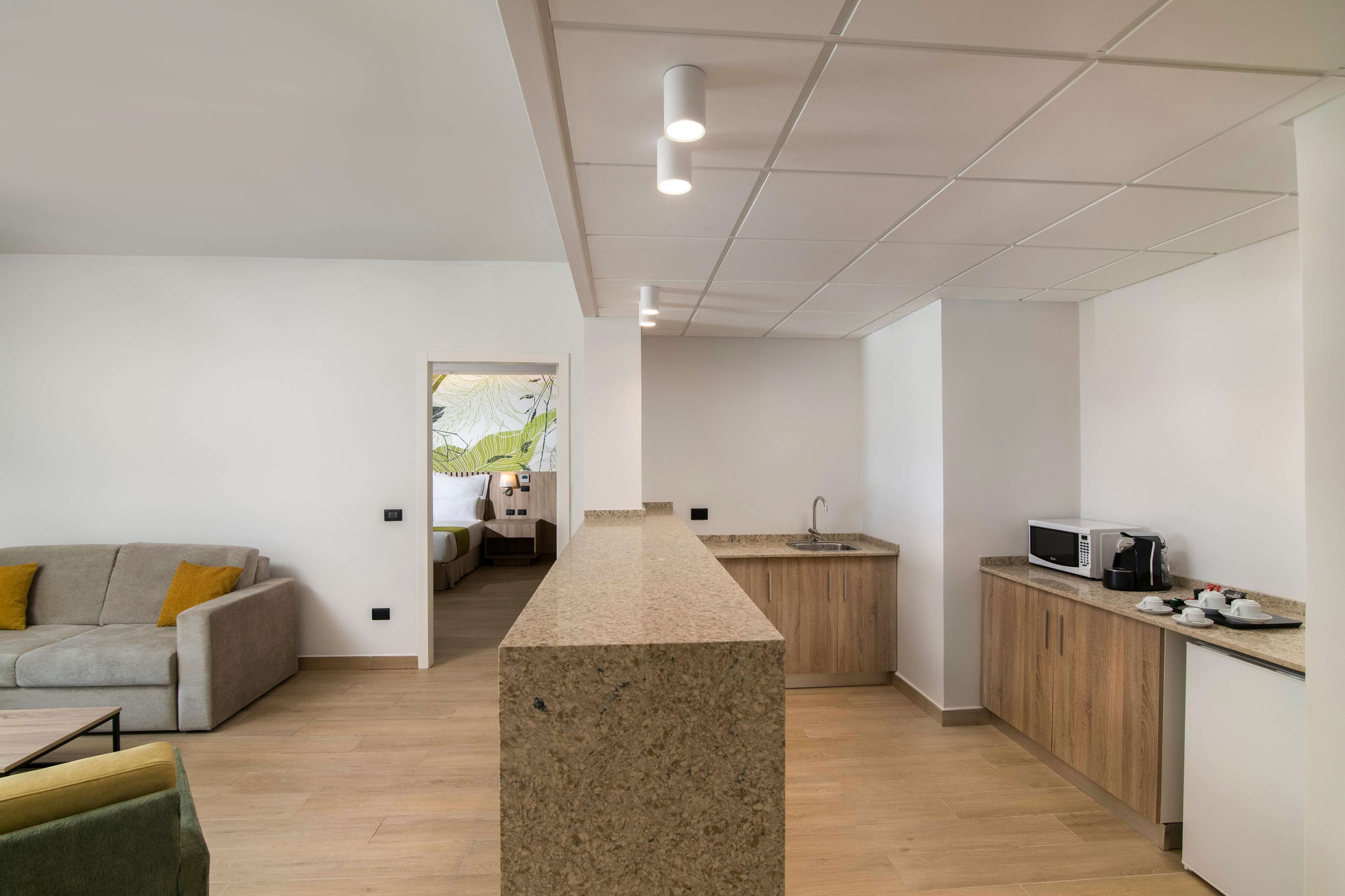 Une cuisine moderne dotée d’un îlot central, d’un coin repas avec un canapé et d’un petit coin cuisine.
