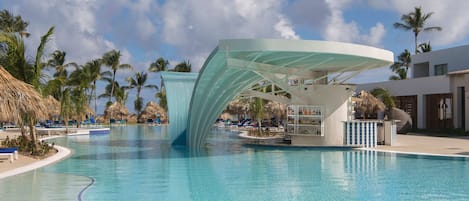 A swimming pool with a modern structure, palm trees, and lounge chairs.