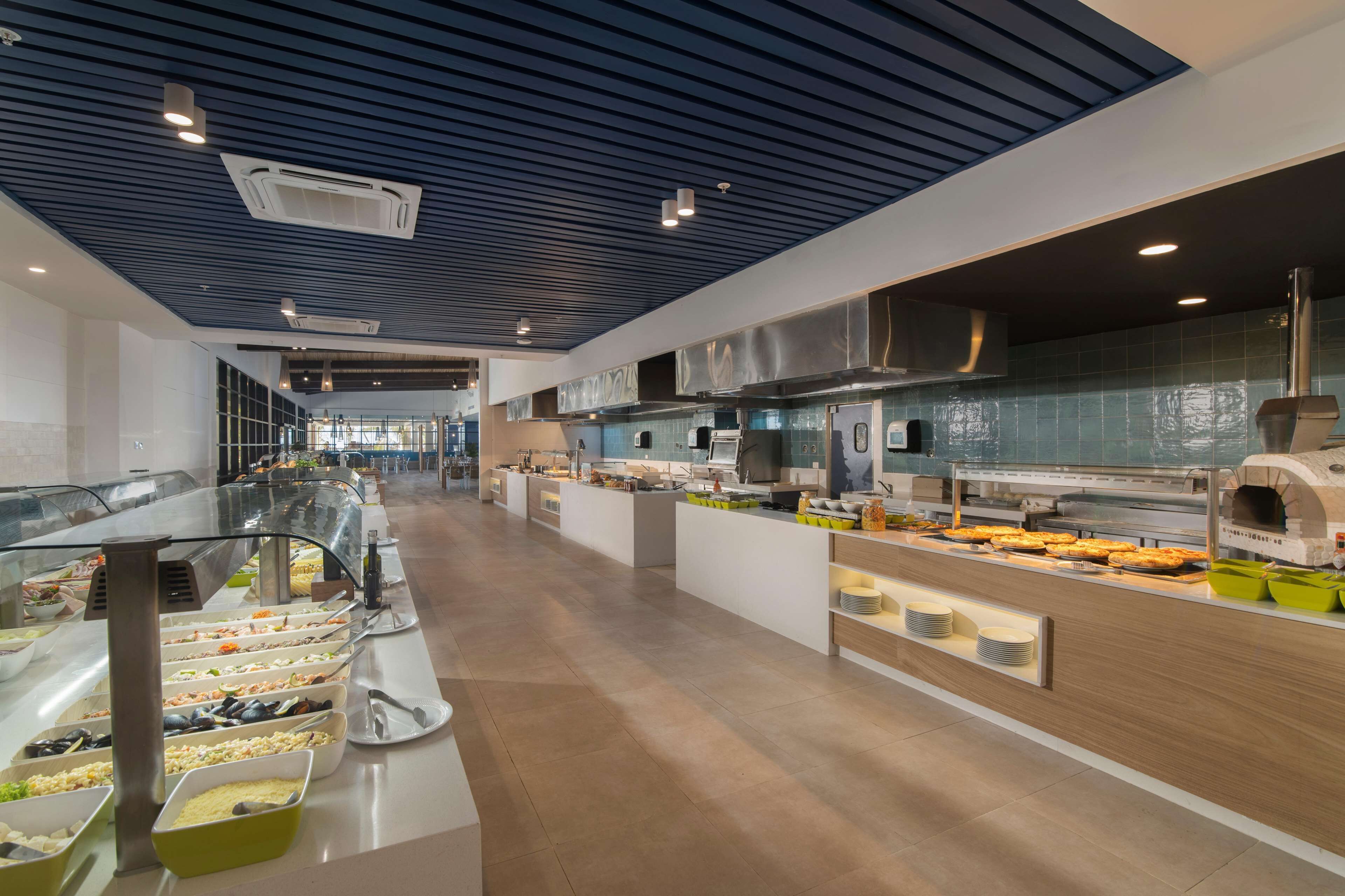 Un buffet moderne, doté de plusieurs présentoirs de nourriture, d’une cuisine ouverte et d’un espace généreux.