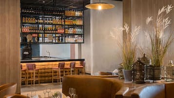 A bar area with shelves of liquor bottles, a bar counter, and seating with a table set for dining.