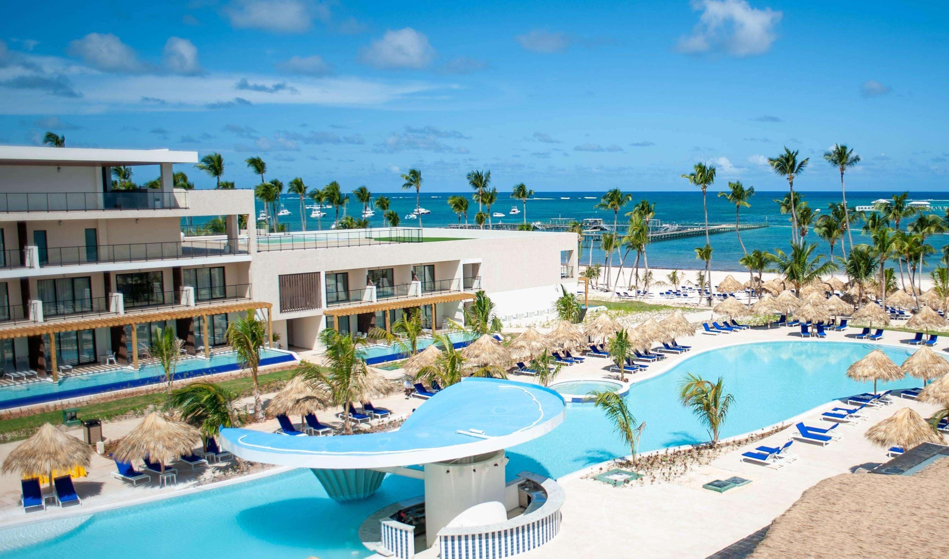 En resort med en stor swimmingpool, flere loungeområder og havudsigt.