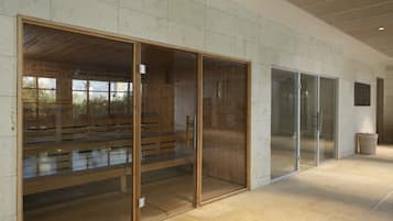 Un interior moderno con bancos de madera y puertas de vidrio, suelo de baldosas y un cubo de basura.