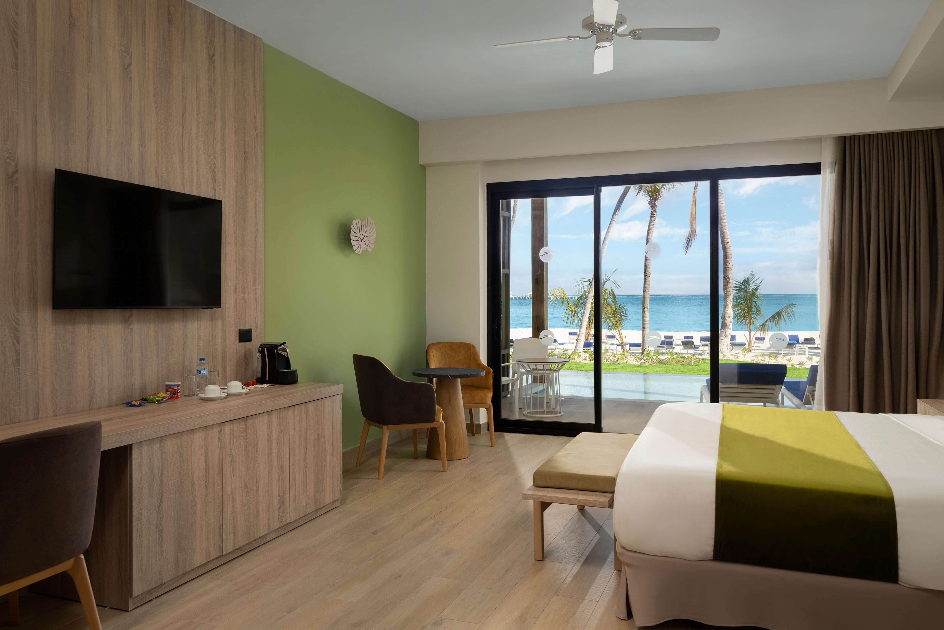 Habitación de hotel con cama, escritorio, silla, televisión y vista al océano.