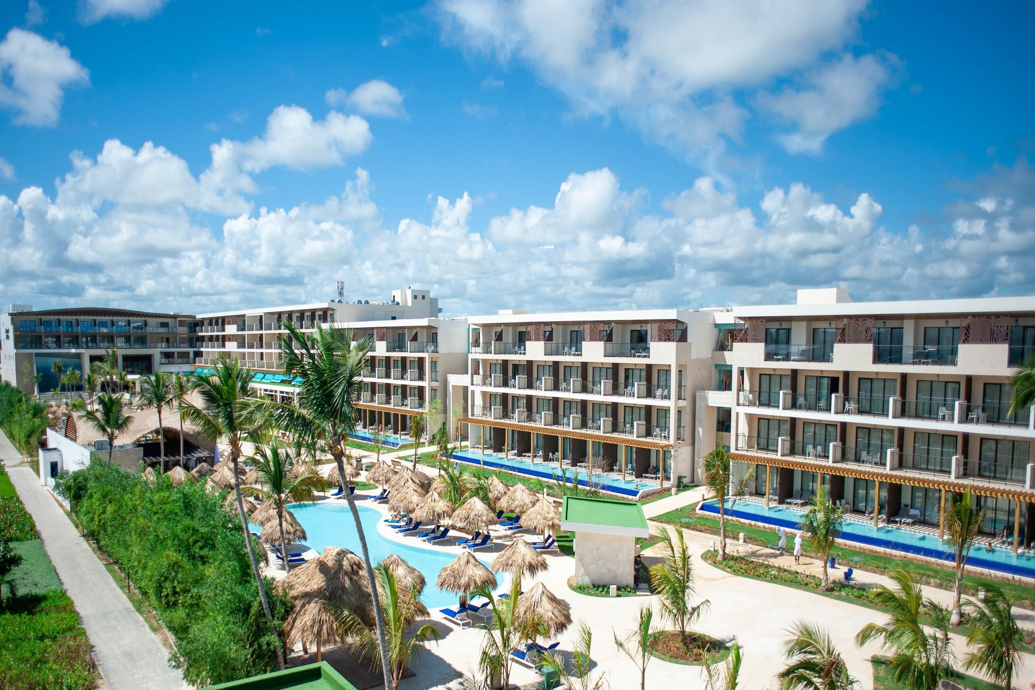 A resort with a swimming pool, palm trees, and modern buildings.