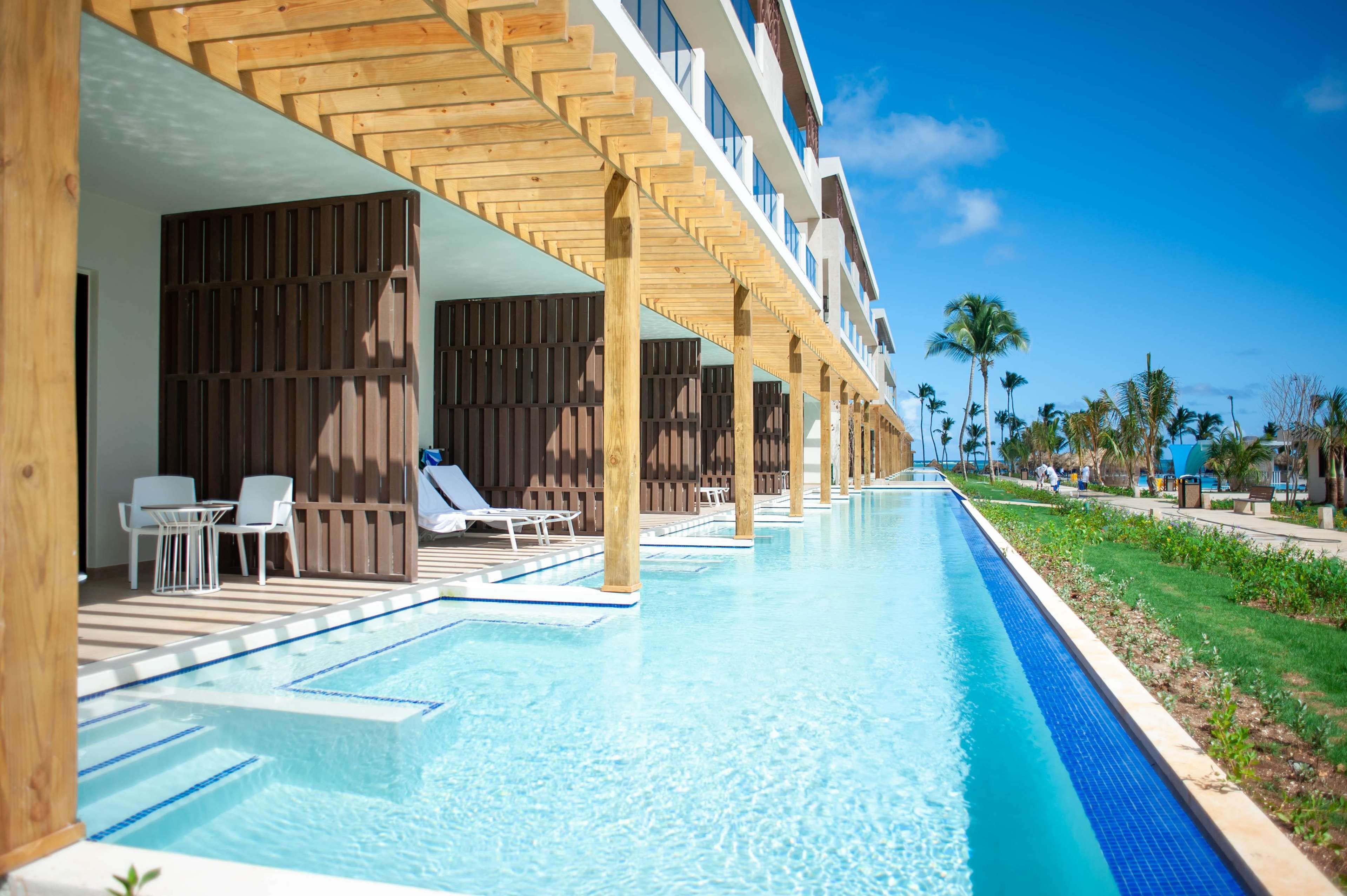 Una piscina con solarium in legno e vista su un edificio di un hotel.