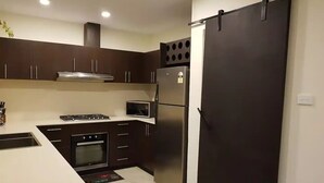 Una cucina moderna con mobili scuri, un frigorifero in acciaio inossidabile, un forno a microonde e un piano cottura.