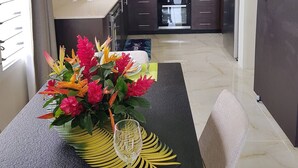 Una cucina moderna con mobili scuri, un'isola centrale e un'area pranzo con un tavolo apparecchiato per due persone.