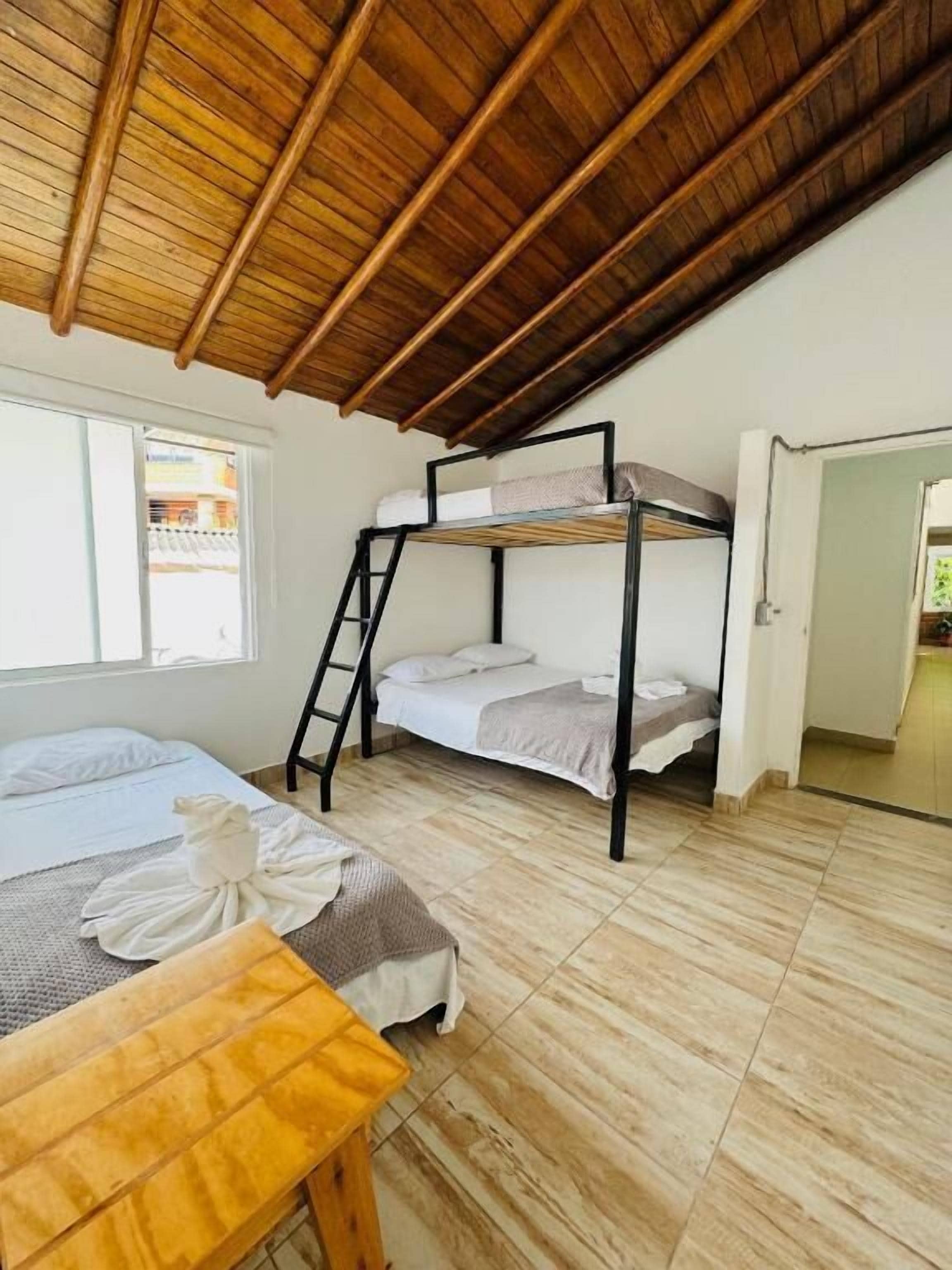 Une pièce avec des lits superposés, une table en bois et une fenêtre.