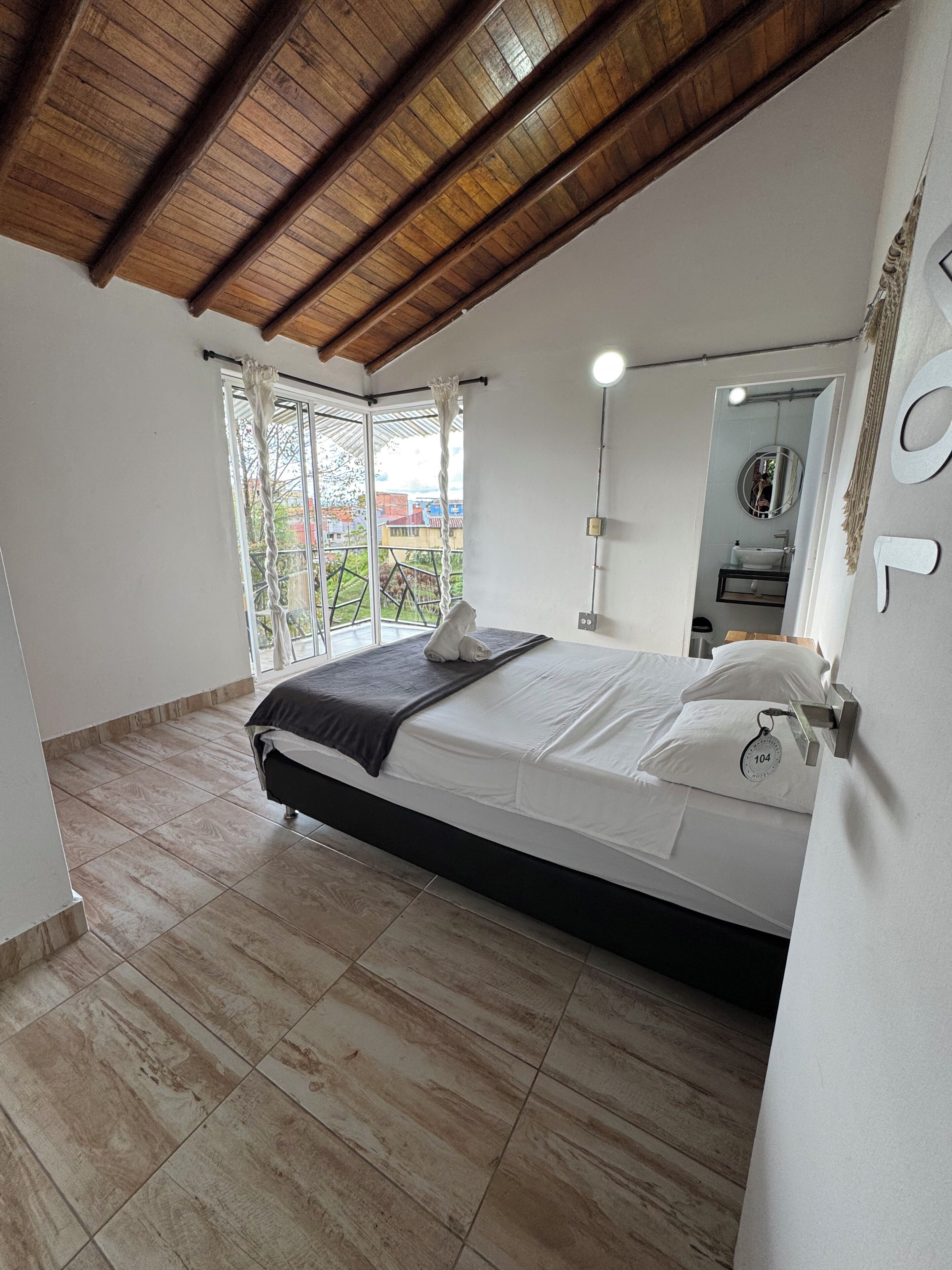 A bedroom with a bed, a window, and a view of the outside.