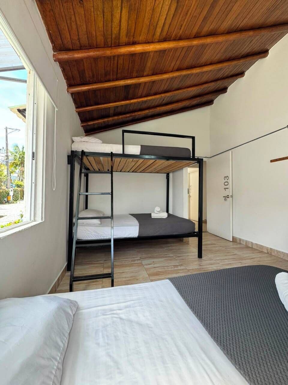 Une chambre avec un lit superposé, un lit simple et une fenêtre donnant sur l’extérieur.