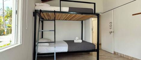Une chambre avec un lit superposé, un lit simple et une fenêtre donnant sur l’extérieur.