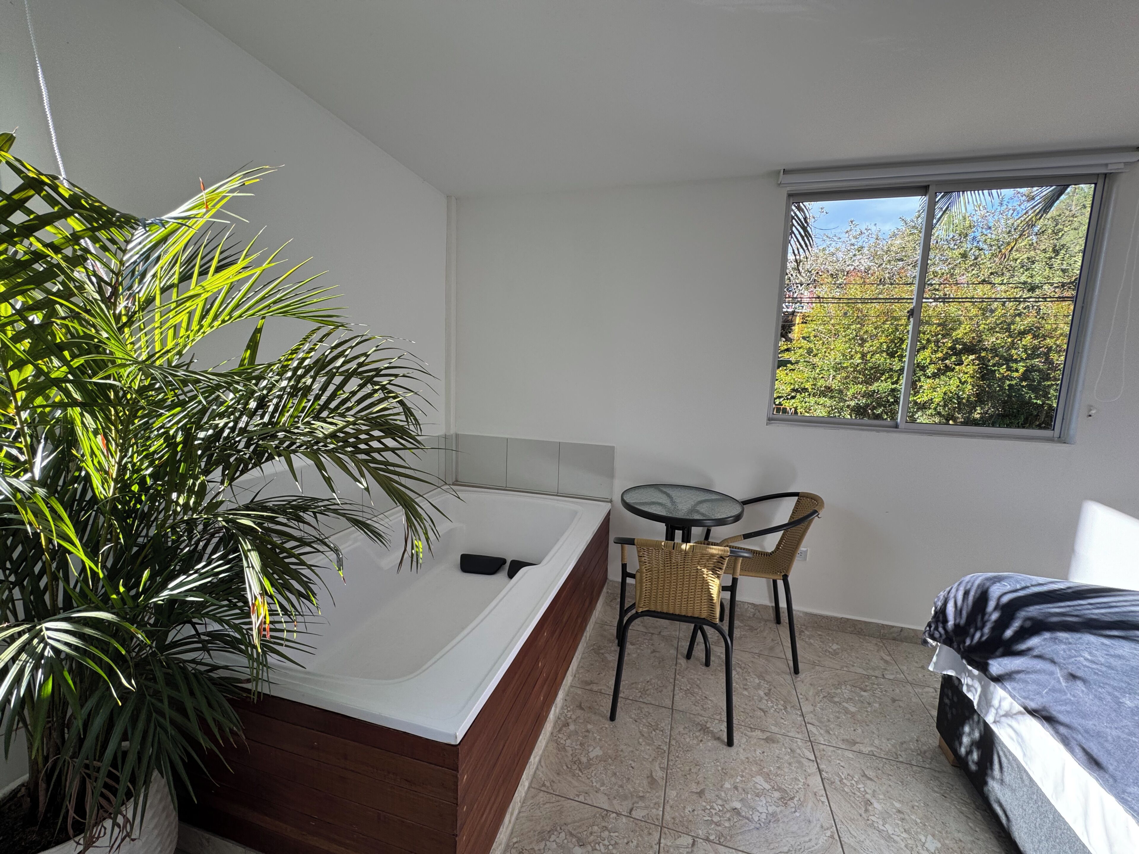 A small, modern room with a single bed, a small table, and a large window.