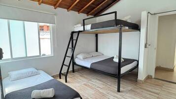 A dormitory room with bunk beds, a ladder, and a window.