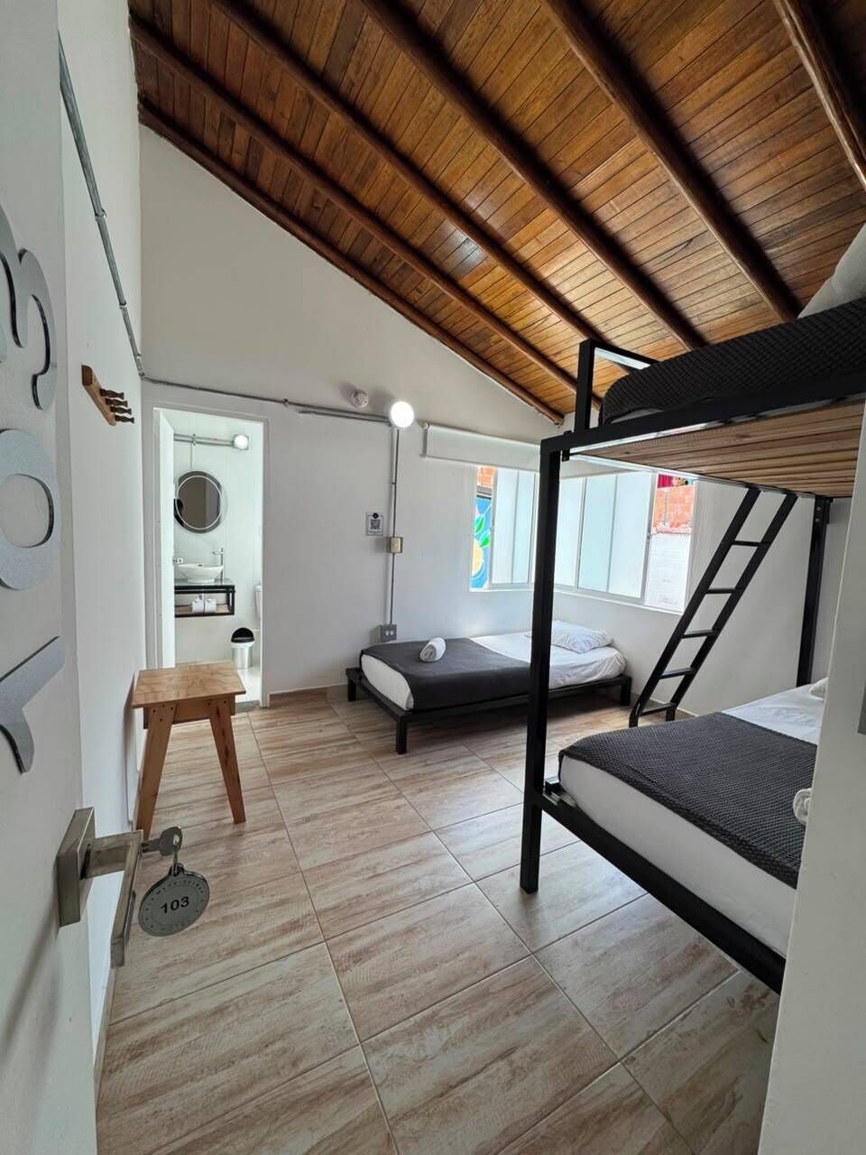 Ein kleines Zimmer mit einem Etagenbett, einem Tisch und einer Tür mit einer Nummer.