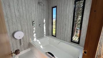 Une salle de bain avec une baignoire, une douche et une fenêtre.