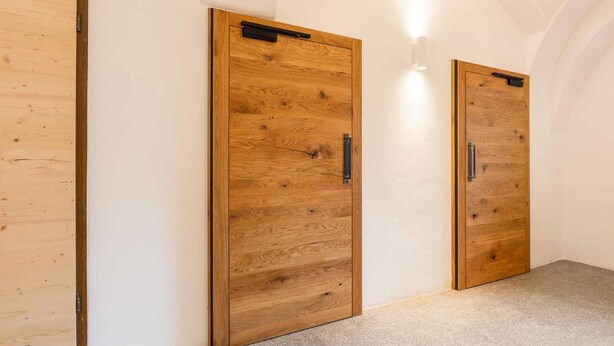 Un couloir avec deux portes en bois, chacune dotée d’une poignée et d’une petite étagère au-dessus de la poignée.
