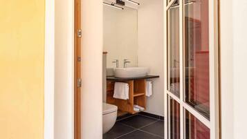Un baño moderno con un lavamanos blanco, dos toalleros, un armario de madera y una cabina de ducha de vidrio.