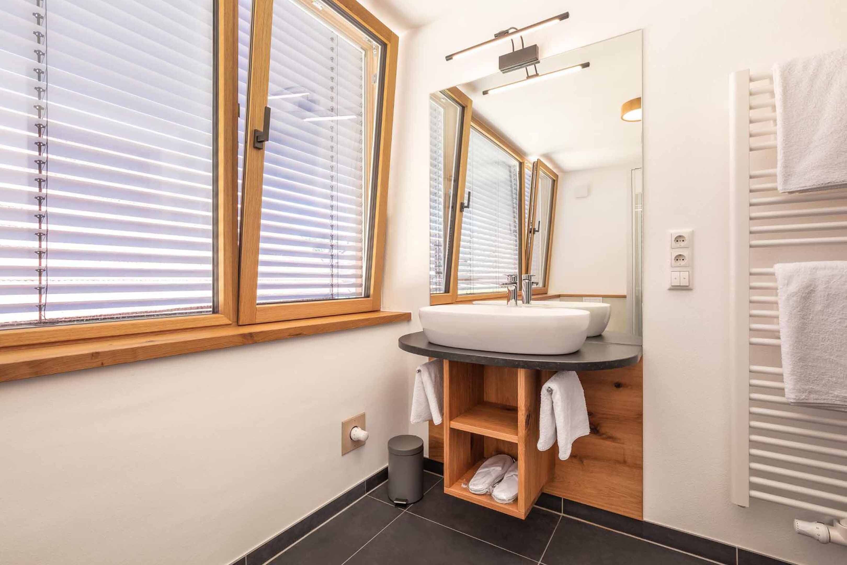 Une salle de bain moderne avec une grande fenêtre, un lavabo, un miroir et un porte-serviettes.